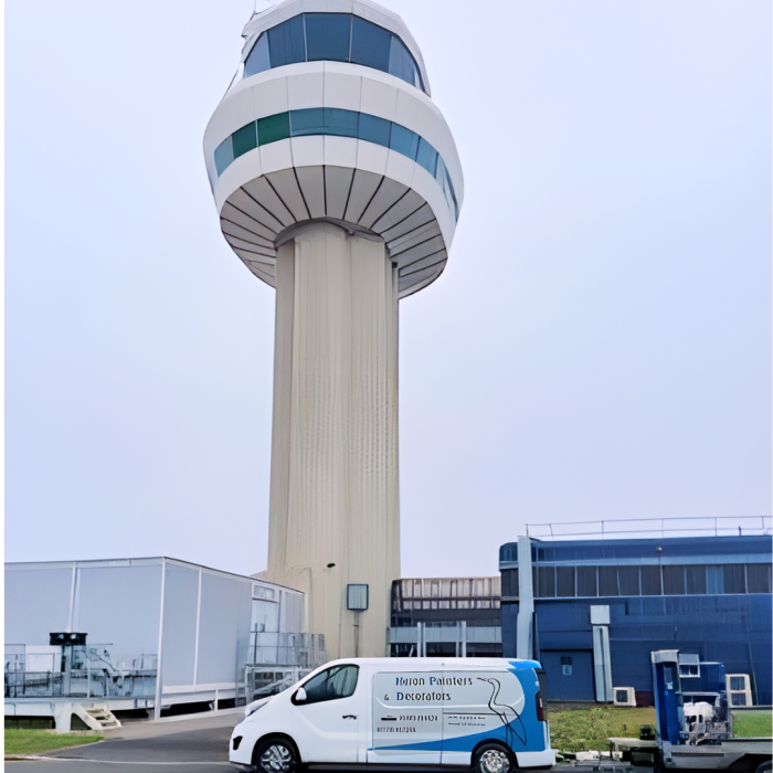 A control tower at gatwick airport on an overcast day with a contractor's blue and white van parked in front of it.